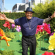 Actor Danny Trejo smiles and holds his arms out in a bright field of flowers.